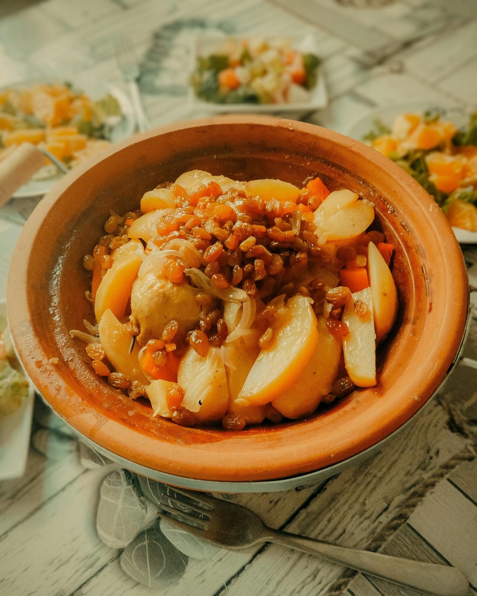 A flavorful Moroccan tajine dish featuring tender potatoes and sweet raisins in a rustic setting.